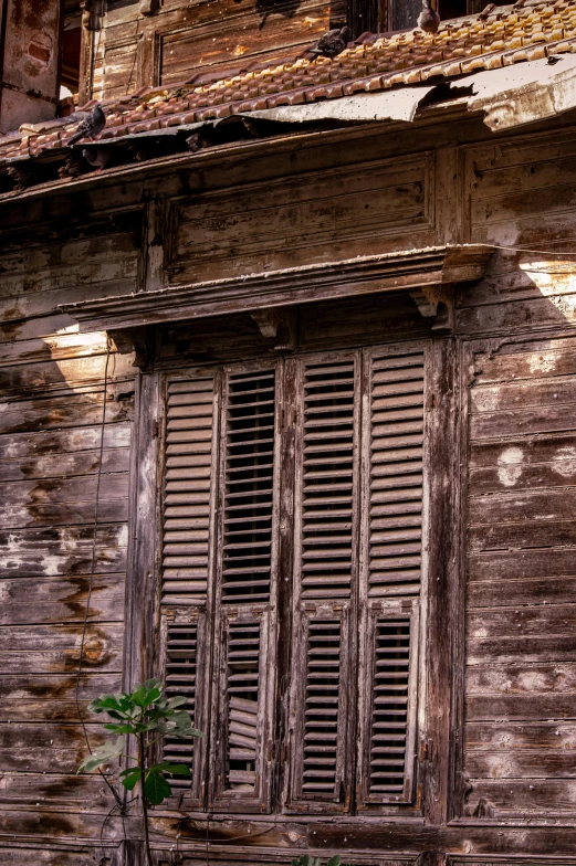 an old building has two windows and shutters on each side