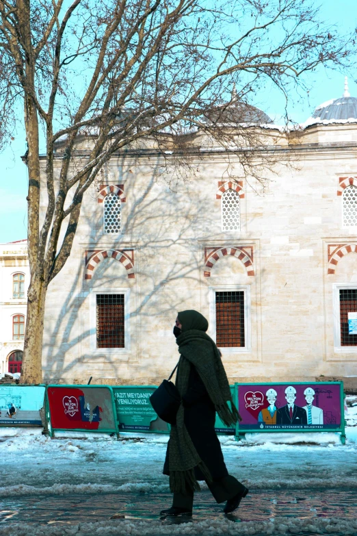 a woman is walking in the snow in front of a large building