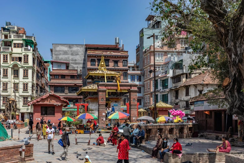 people walking and sitting in a courtyard surrounded by buildings