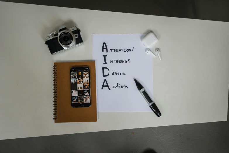 a po camera, notebook and pen laying on top of a desk