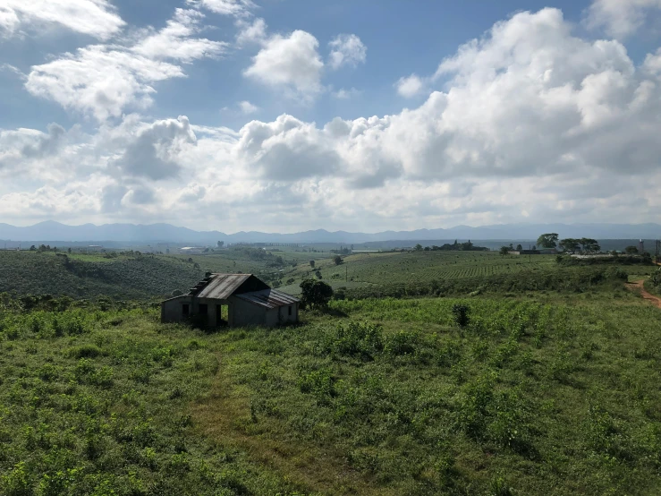 a shack is out in a field on a partly cloudy day