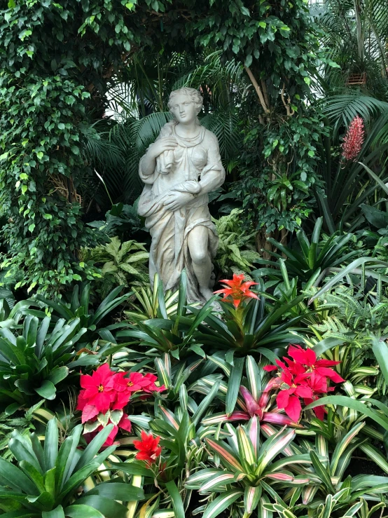 the statue is surrounded by many plants and flowers