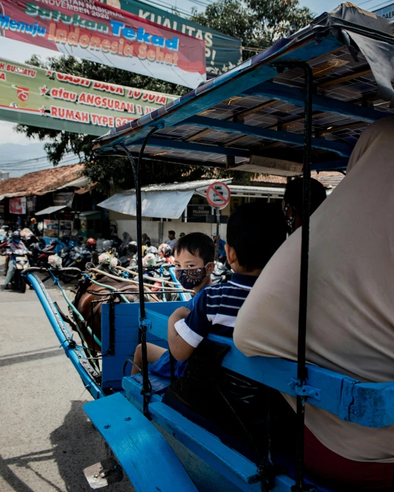 people in blue carts sitting outside at a market