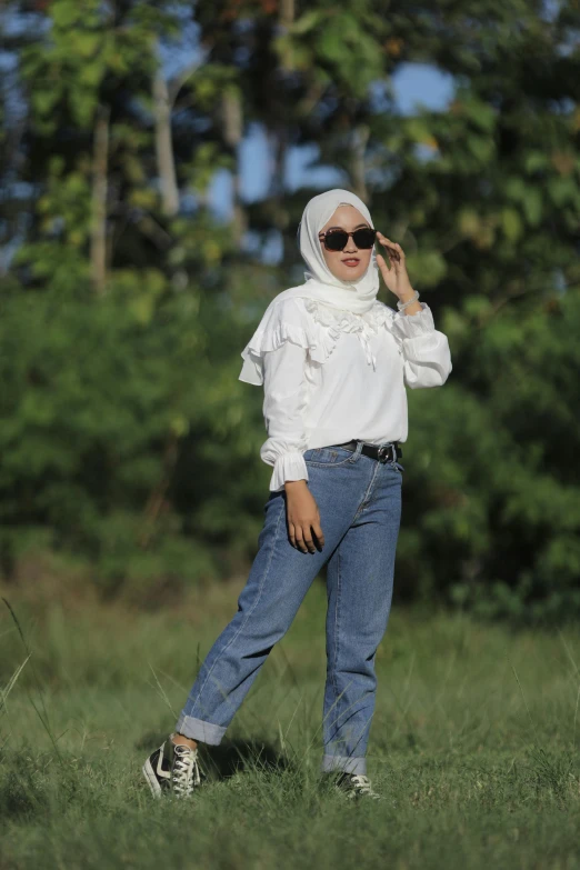 a girl with a hijab and sunglasses posing in the field