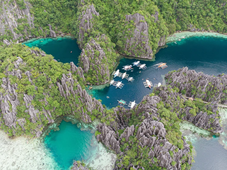 an aerial view of several boats in a lake surrounded by rocks