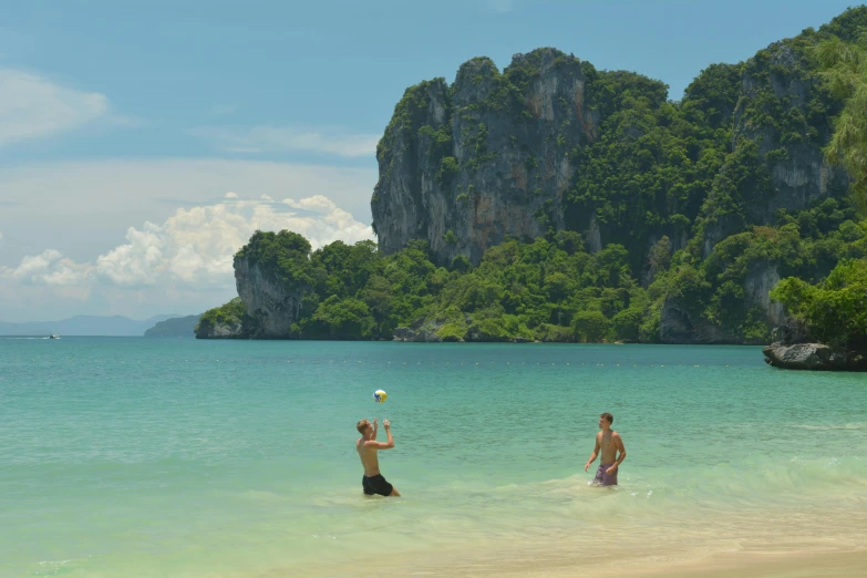 two people standing in water by an island