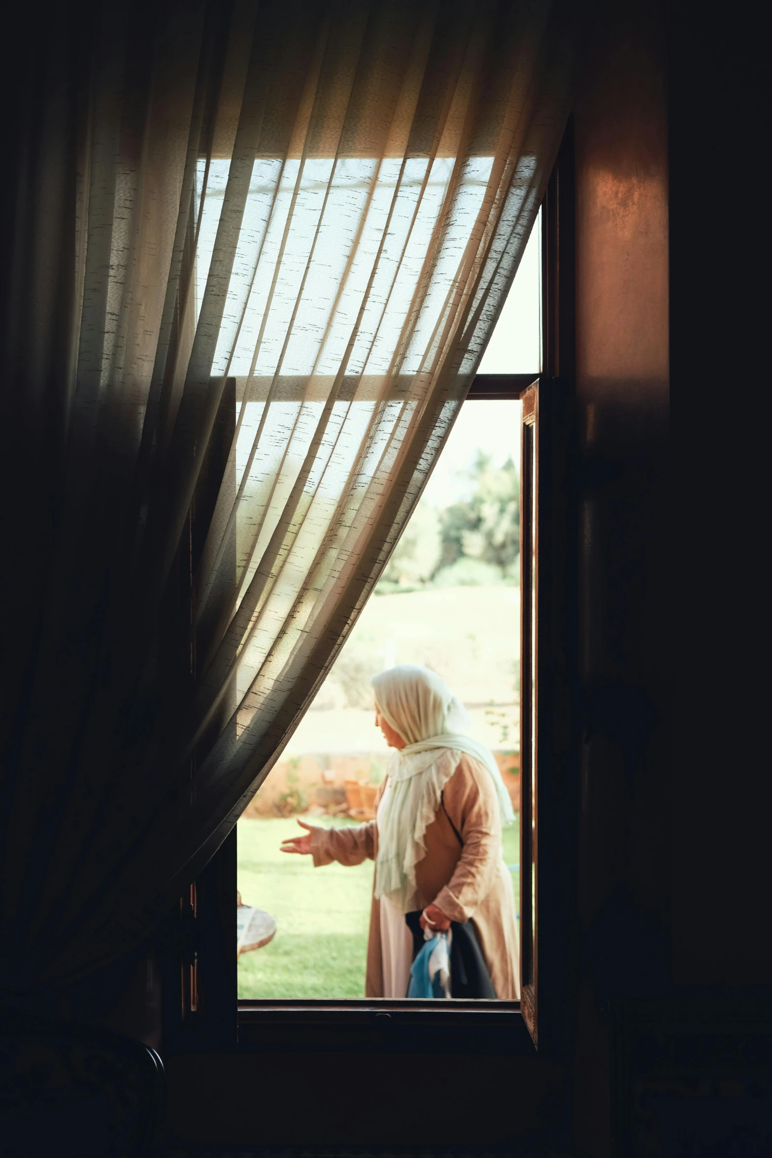 an old woman standing by the window outside