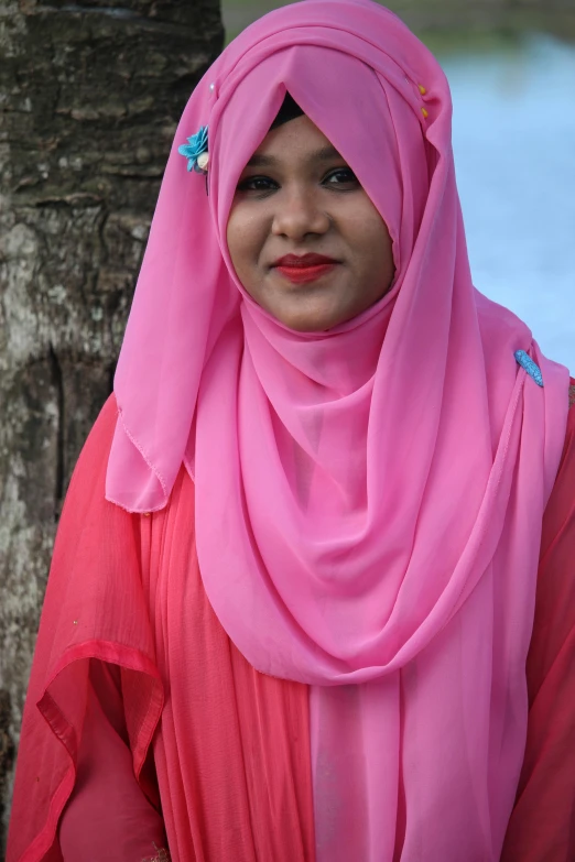 a woman in a pink headscarf smiles for the camera