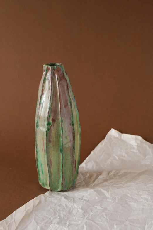 a green vase that is sitting on some white paper