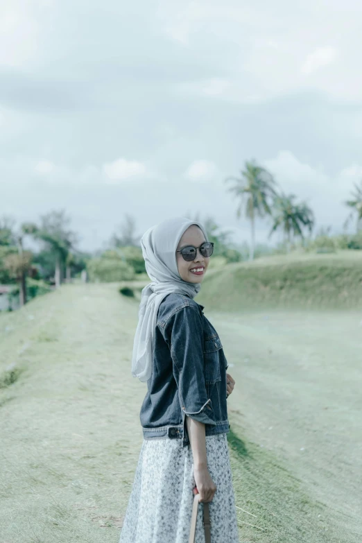 woman in glasses standing in front of an open field