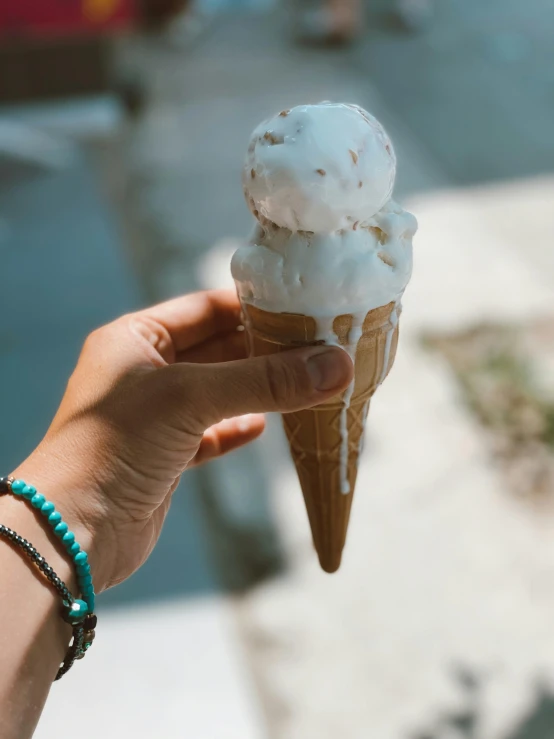 a hand holds an ice cream cone with a bite out