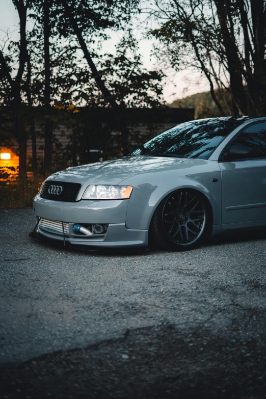 a car parked in a lot in front of some trees