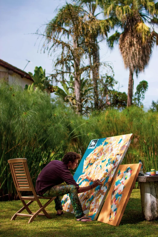 man painting a picture with a palette in his backyard