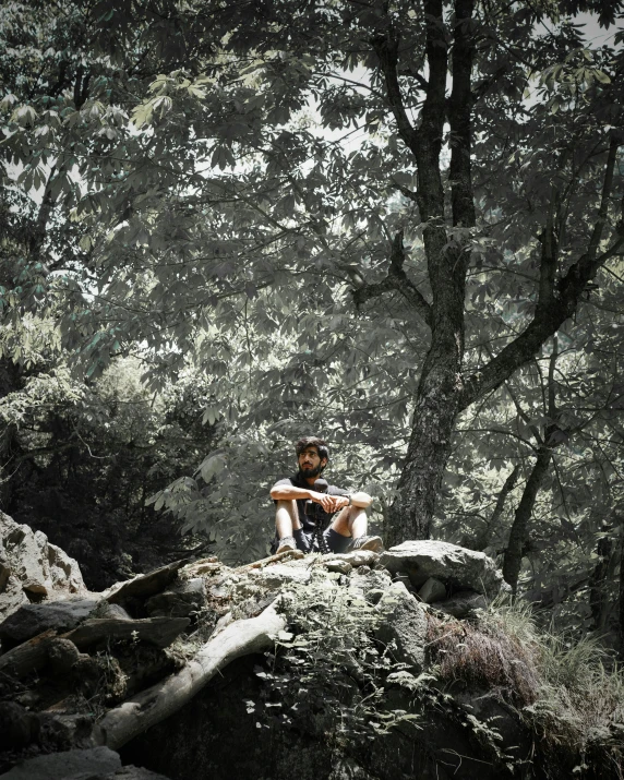 a woman sitting on a large rock in the woods