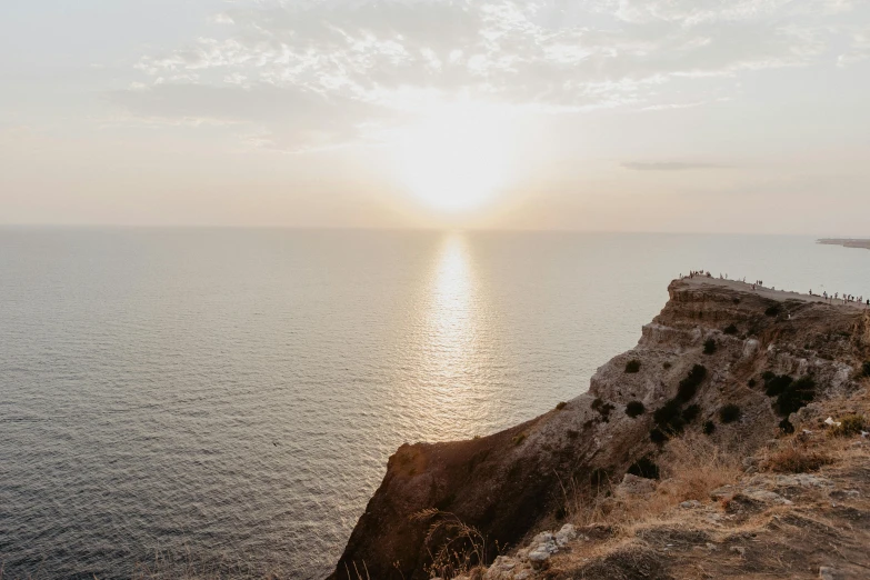 people walking along the side of a cliff in the water