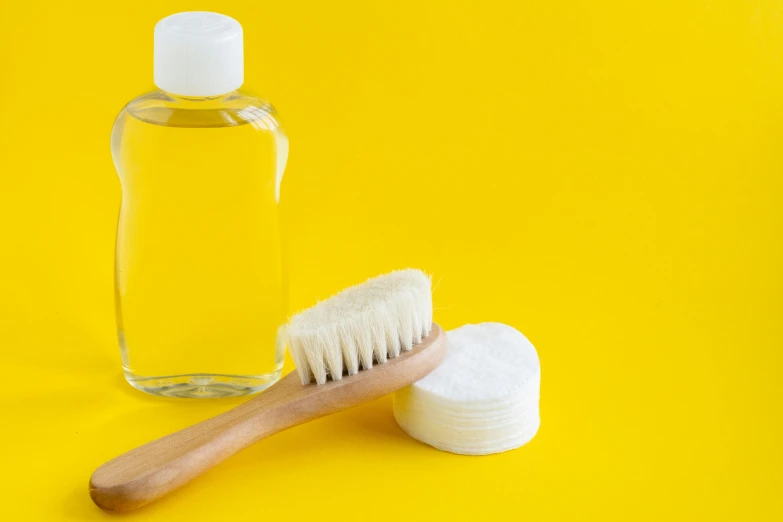 a bottle of lotion and tooth brush are on a yellow background