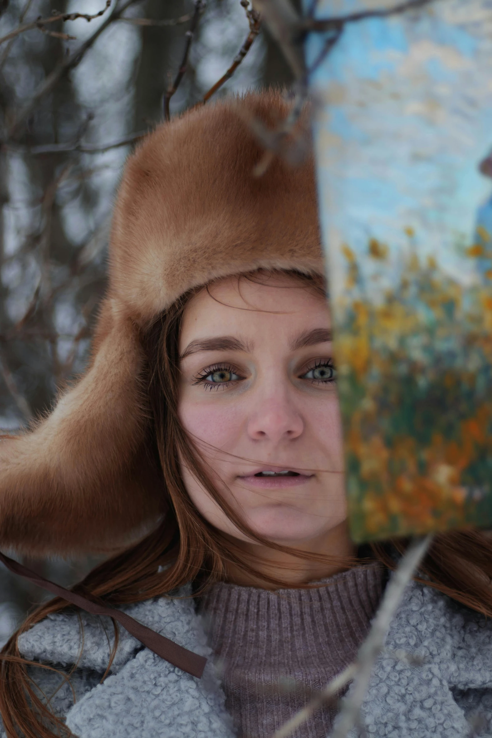 a young woman standing in front of a forest in a brown coat and furry hat