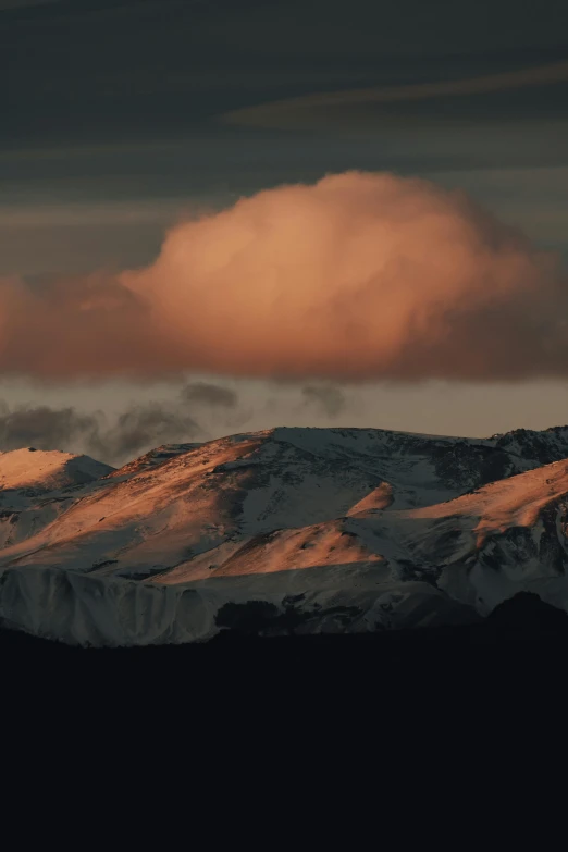 a snowy mountain is shown under a cloudy sky