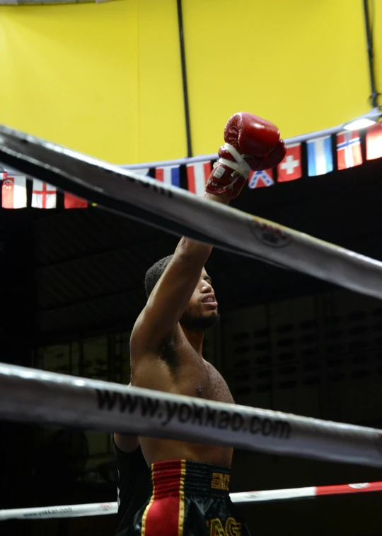 man at the gym raises his arms in the air in preparation to beat a boxing