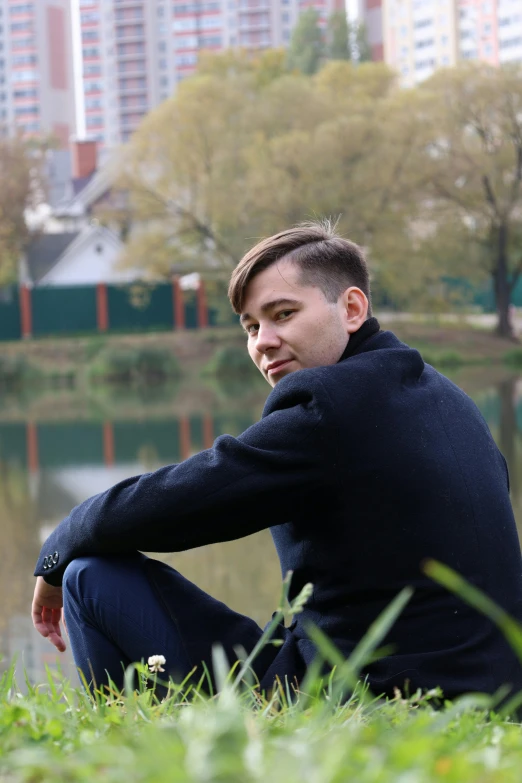 a man sitting in front of water next to a tall building