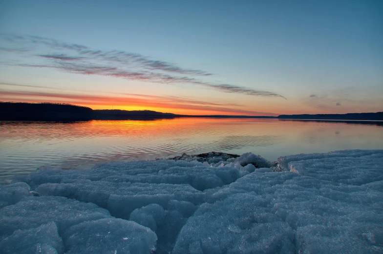 the sun is setting over the lake and snow