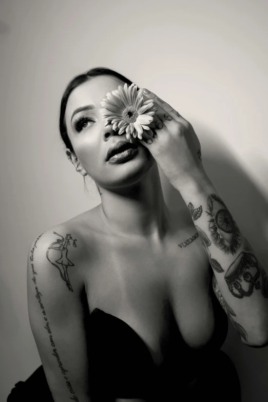 a woman with a tattooed arm holding a flower