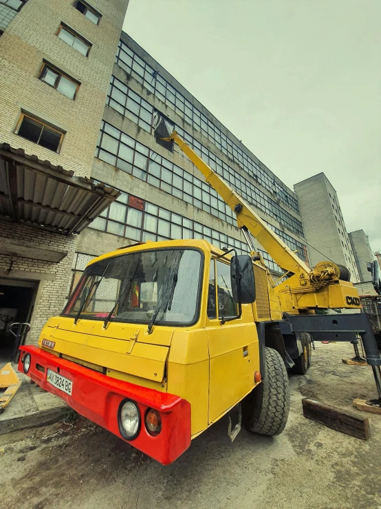 a large yellow truck parked in front of a tall building