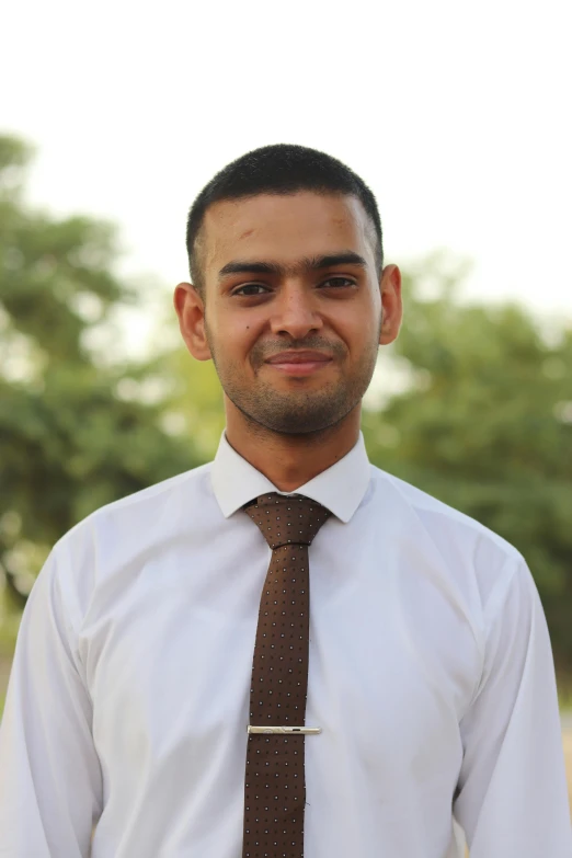 a young indian man wearing a brown tie and a white shirt
