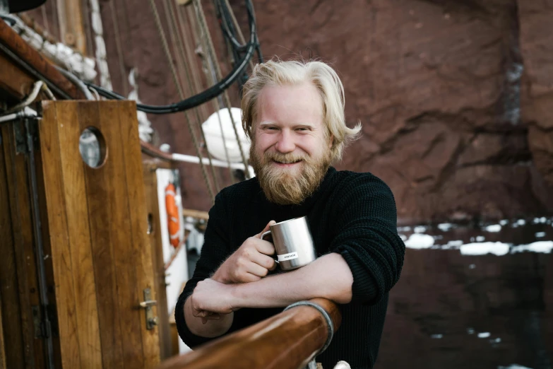 a man with long hair and beard holding a mug