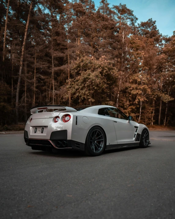 a white sports car parked in front of some trees