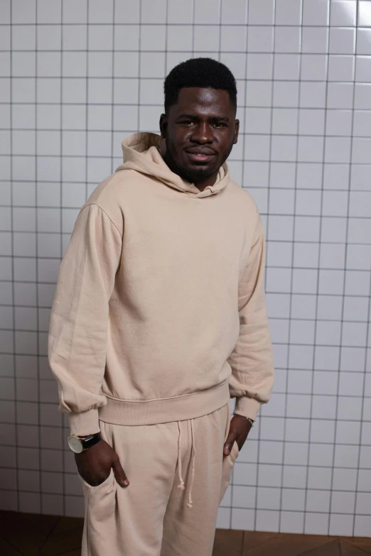 man in beige sweater and light colored sweat pants posing for camera