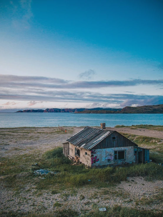 an abandoned house on the beach with the water in the background