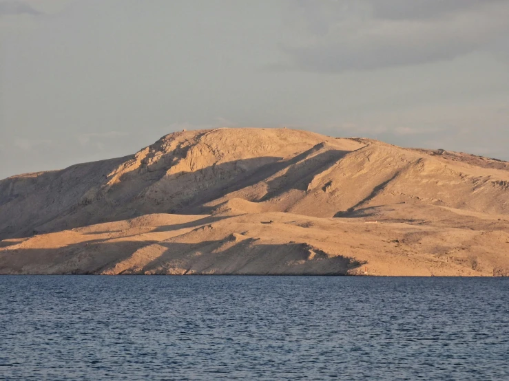 mountains rise above the blue water near the sand