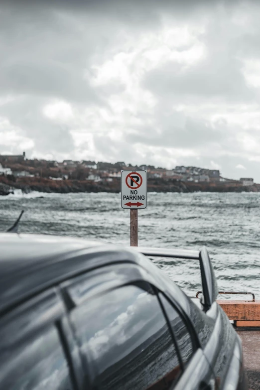 a parking sign by the ocean and a car