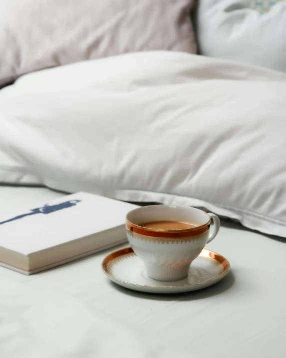 coffee mug with a saucer on top of a bed
