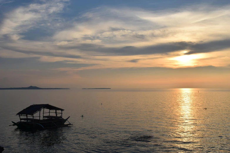 a boat sitting on the shore as the sun sets