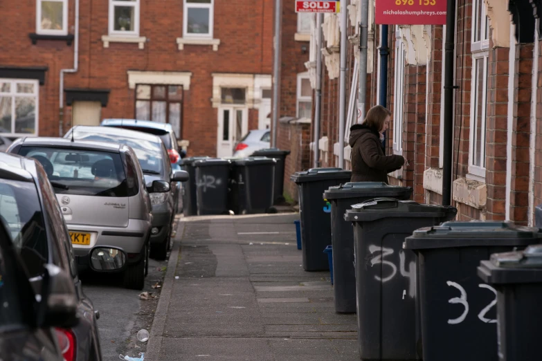 a man standing next to a row of trash cans