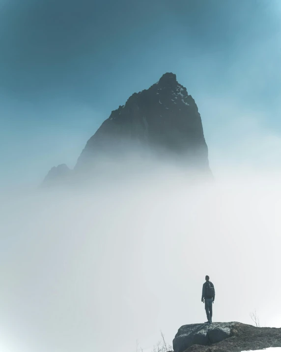 a person in winter gear stands on the edge of a cliff