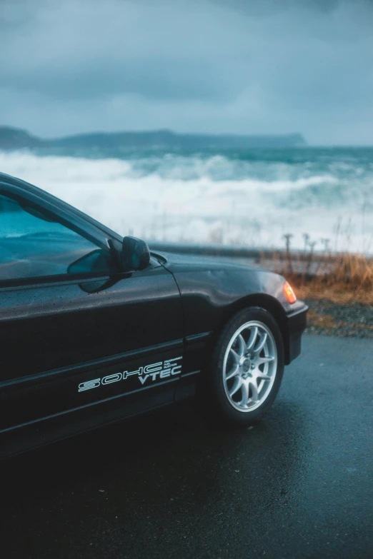 black sports car parked near an ocean shore