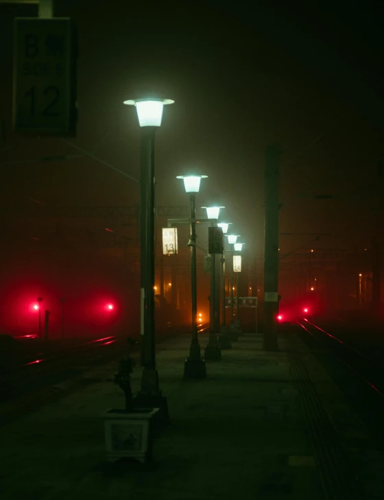 train tracks at night with street lights in the fog