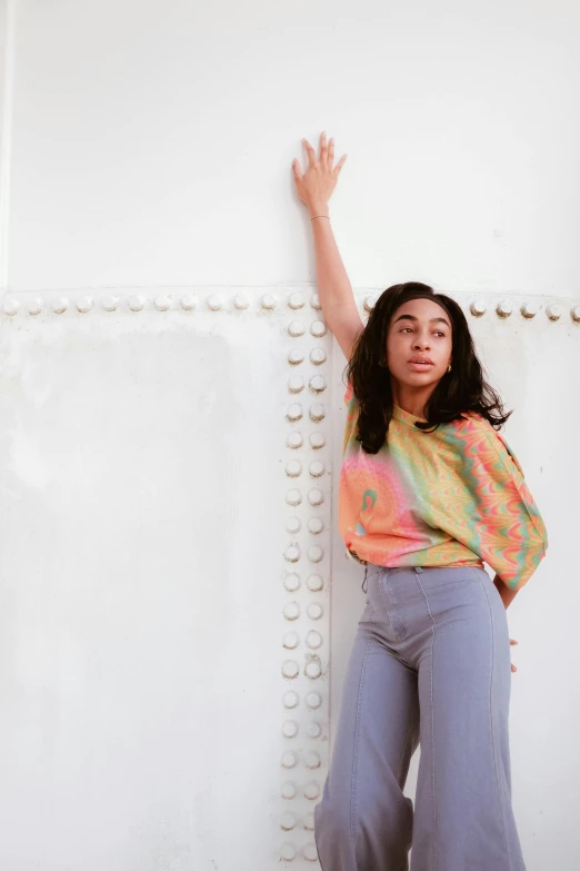 the woman is leaning against a wall with her hands up