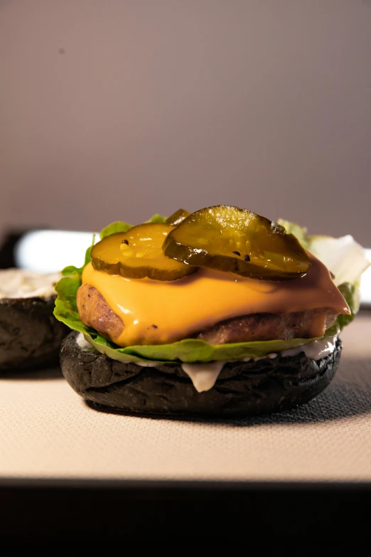 a hamburger with green pepper and pickle on a black rock