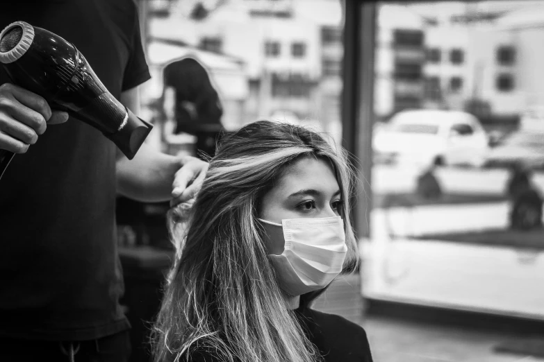 a woman in a face mask with a hair dryer in her hand