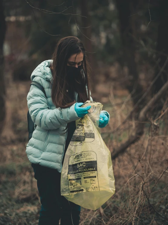 a woman is picking up a bag of trash from the ground