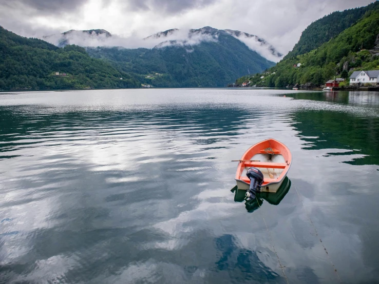 an orange boat floats in the calm water