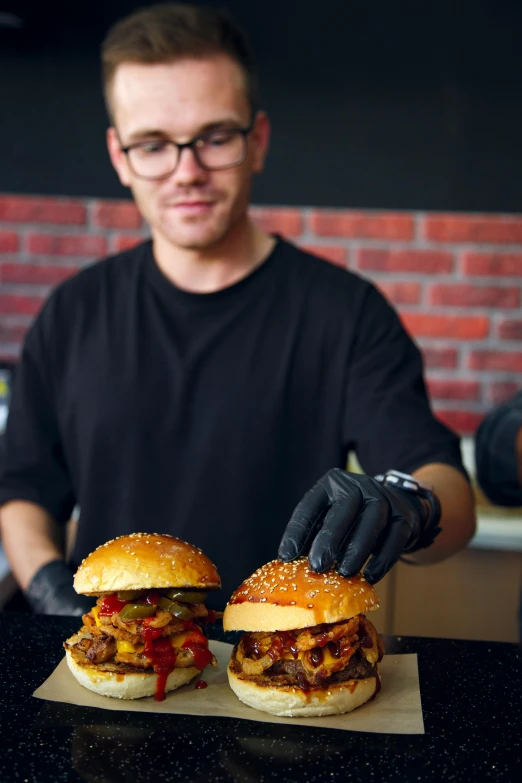 a man who is cooking sandwiches is putting sauce on them