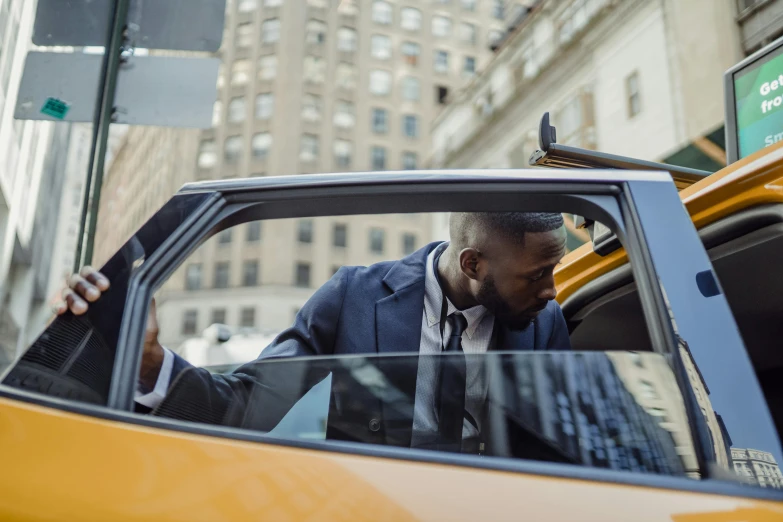 a black man sitting in the driver seat of a taxi cab