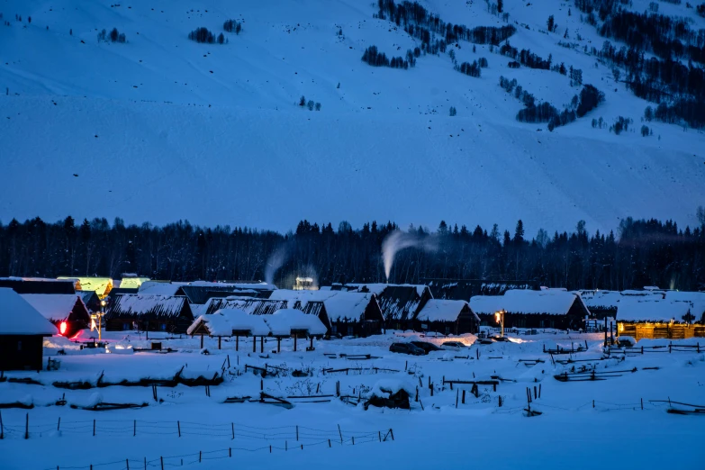 a snow covered town in the night lit up with smoke