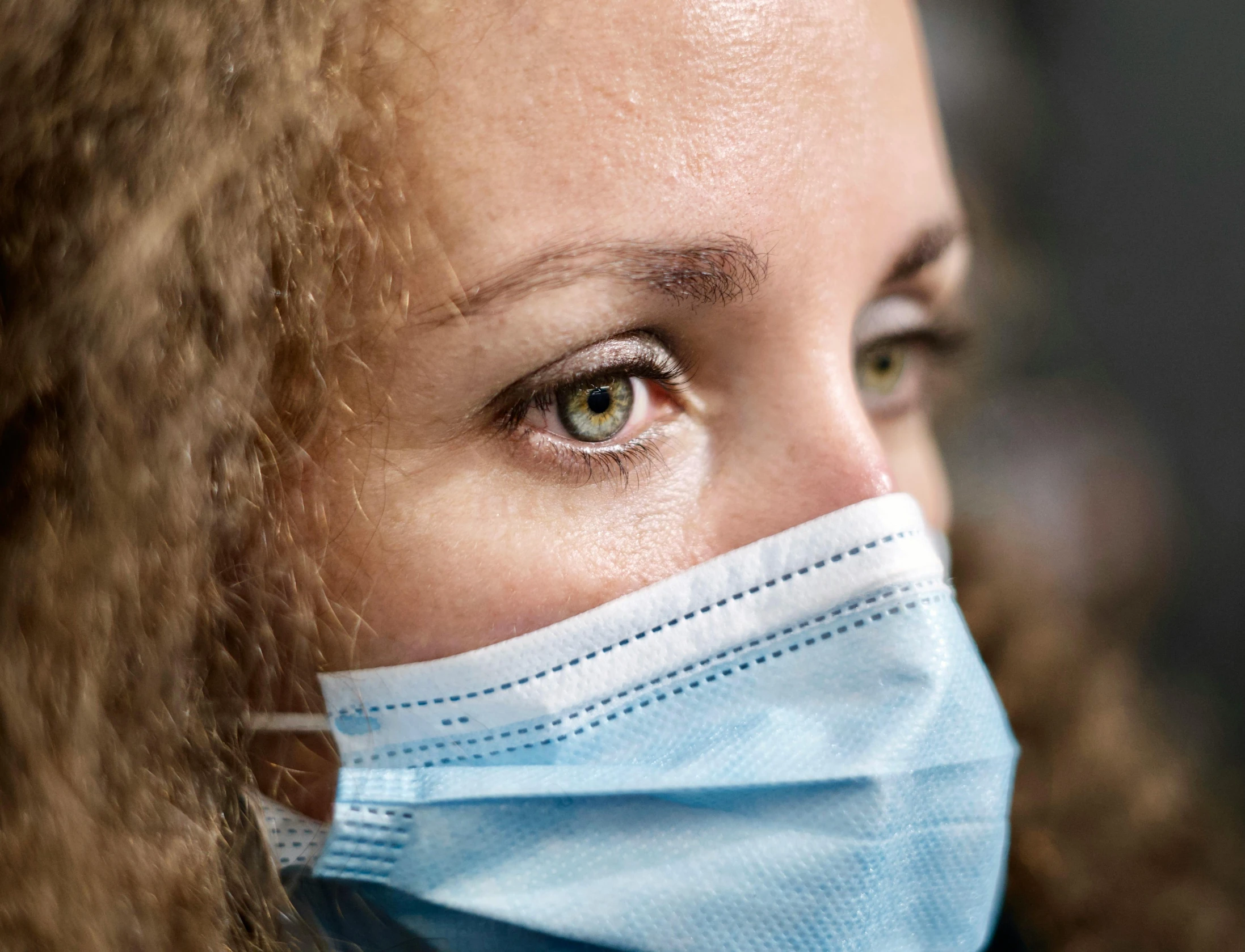 a woman wearing a surgical mask looking into the distance