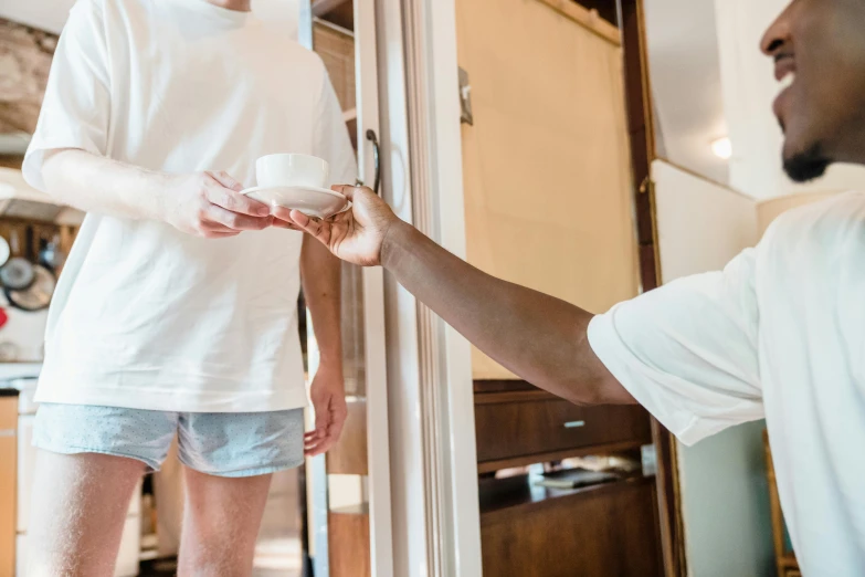 two people holding a cup and looking into a doorway